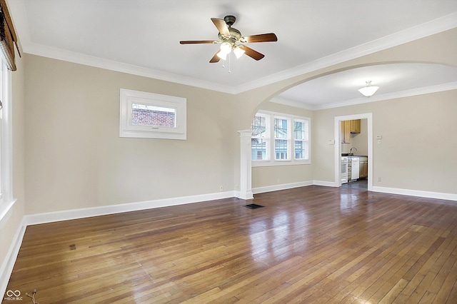 spare room with arched walkways, wood-type flooring, and baseboards