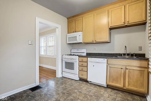 kitchen with dark countertops, visible vents, a sink, white appliances, and baseboards