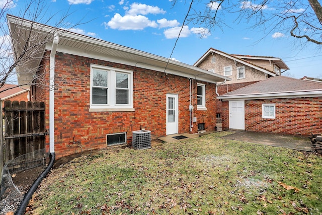 rear view of property featuring brick siding, a patio, a yard, central AC unit, and fence