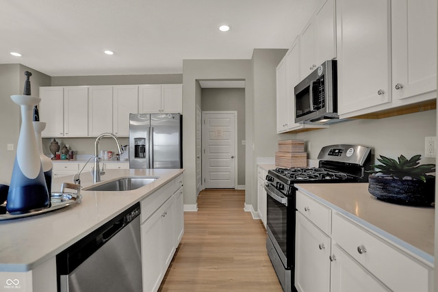 kitchen with white cabinetry, stainless steel appliances, a sink, and light countertops