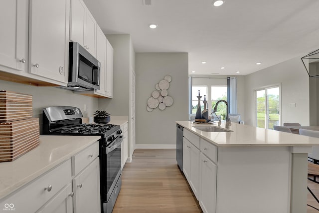 kitchen featuring recessed lighting, stainless steel appliances, a sink, light wood finished floors, and an island with sink