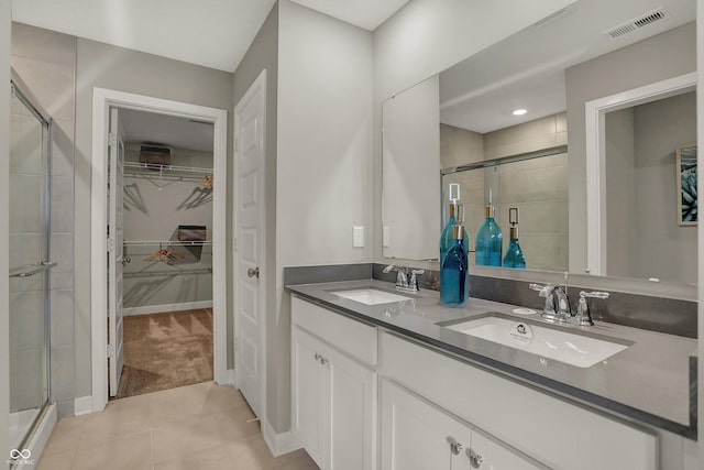 full bathroom with a walk in closet, a sink, visible vents, and a shower stall