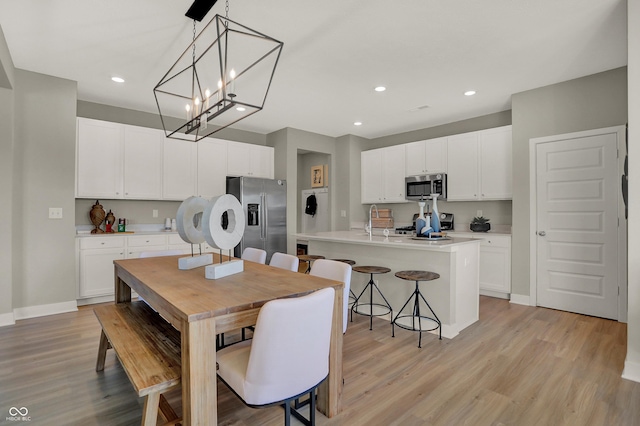 dining area with baseboards, light wood finished floors, and recessed lighting