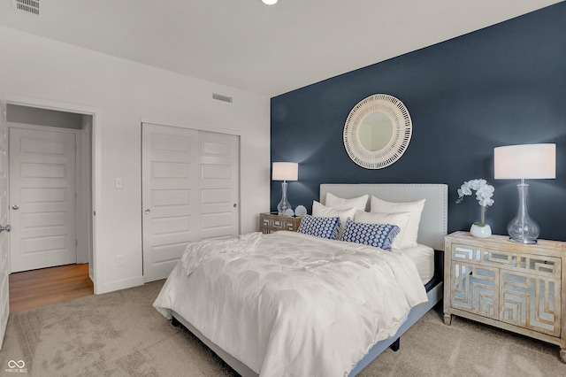 carpeted bedroom with a closet, visible vents, and baseboards