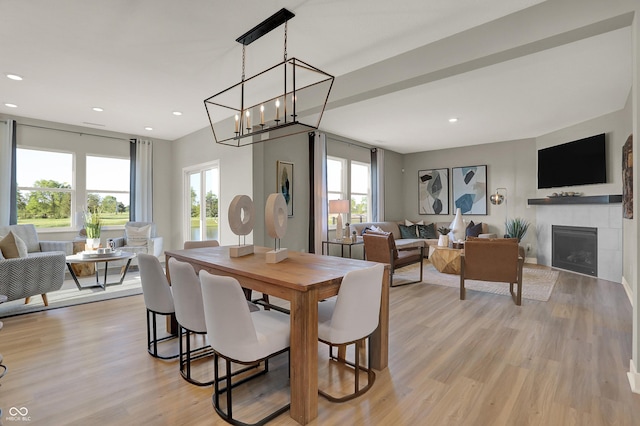 dining room featuring light wood finished floors, a wealth of natural light, a tiled fireplace, and recessed lighting