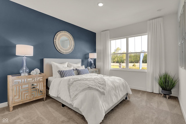 carpeted bedroom featuring an accent wall and baseboards