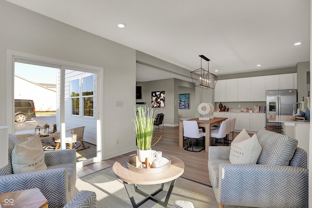 living room with light wood-style floors, recessed lighting, a notable chandelier, and baseboards