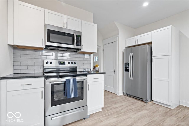 kitchen featuring stainless steel appliances, white cabinetry, light wood-style floors, and decorative backsplash