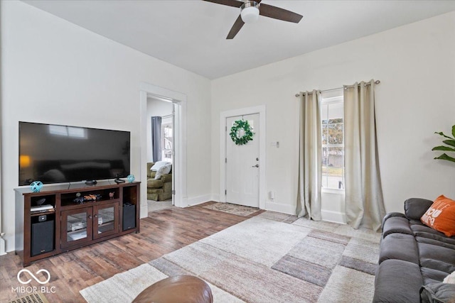 living area featuring ceiling fan, baseboards, and wood finished floors