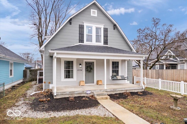 dutch colonial featuring a porch, roof with shingles, and fence