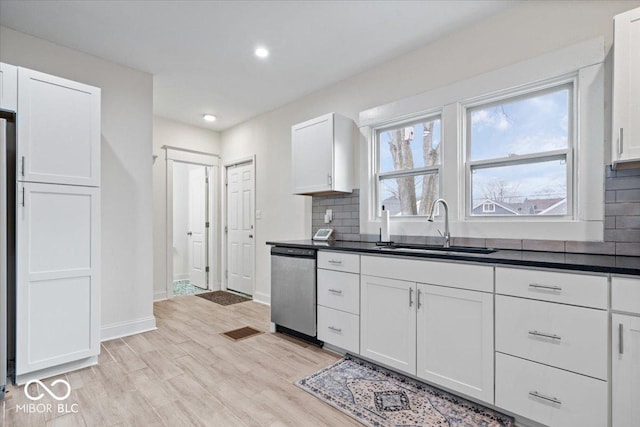 kitchen with a sink, dark countertops, decorative backsplash, and stainless steel dishwasher