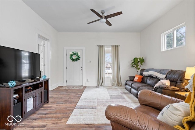 living room featuring ceiling fan, baseboards, and wood finished floors