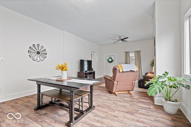 living area featuring light wood-type flooring, baseboards, and a ceiling fan