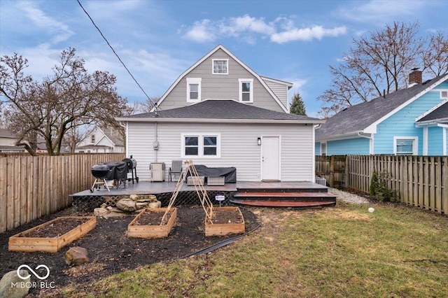 back of house with a garden, a lawn, a deck, and a fenced backyard