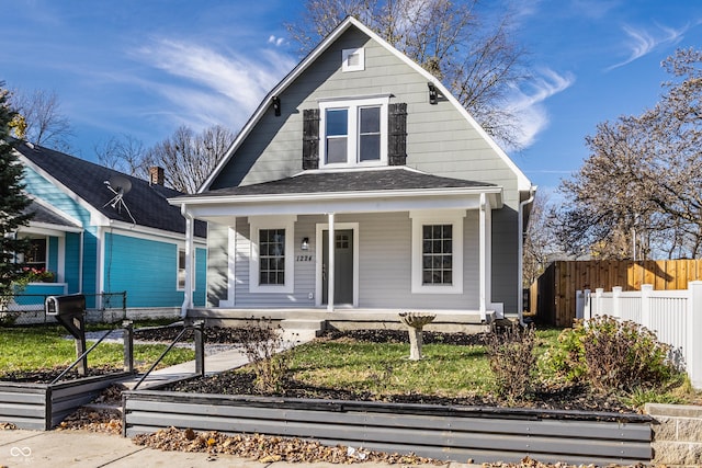 dutch colonial with covered porch, a vegetable garden, fence, and a shingled roof