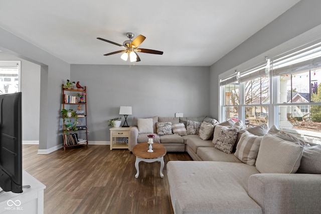 living room featuring ceiling fan, baseboards, and dark wood-style flooring