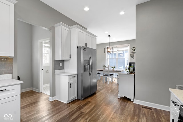 kitchen with visible vents, light countertops, backsplash, a wealth of natural light, and stainless steel fridge with ice dispenser