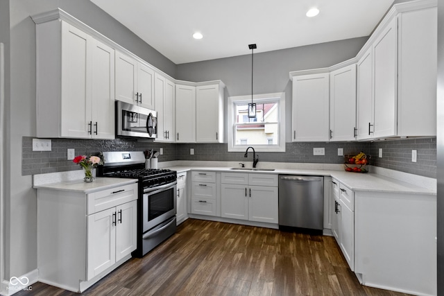 kitchen with white cabinets, appliances with stainless steel finishes, dark wood finished floors, and a sink