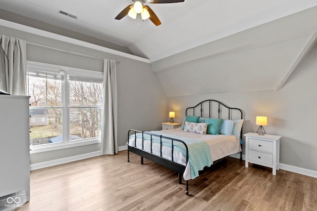 bedroom with lofted ceiling, multiple windows, visible vents, and wood finished floors