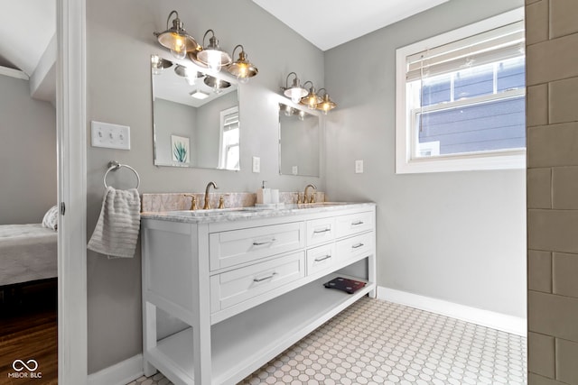 bathroom with a sink, ensuite bath, baseboards, and double vanity