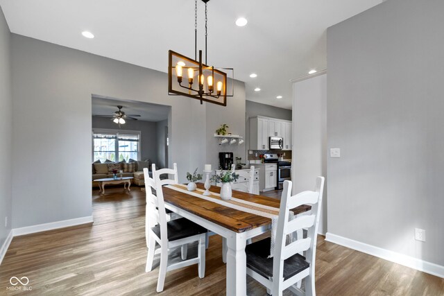 dining room featuring light wood-type flooring, ceiling fan with notable chandelier, baseboards, and recessed lighting