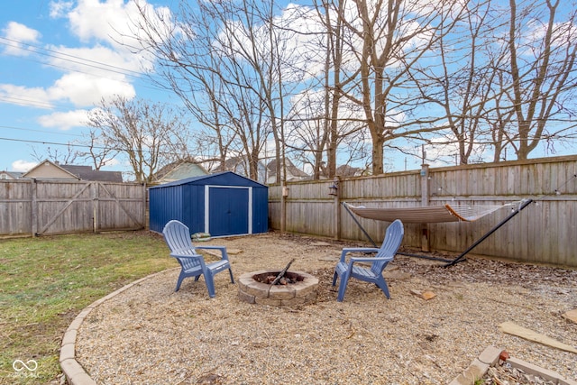 view of yard with a fire pit, a fenced backyard, a shed, and an outbuilding