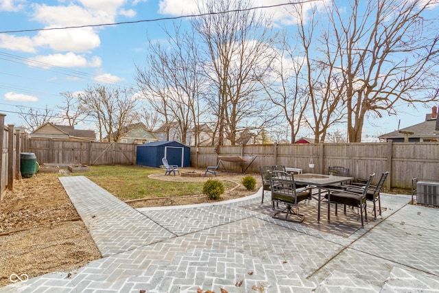 view of patio with an outbuilding, a fenced backyard, central air condition unit, a shed, and outdoor dining space