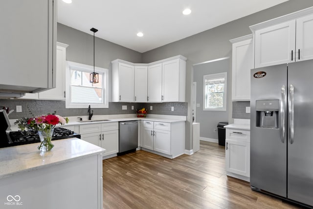 kitchen featuring tasteful backsplash, light wood-style flooring, appliances with stainless steel finishes, white cabinets, and a sink