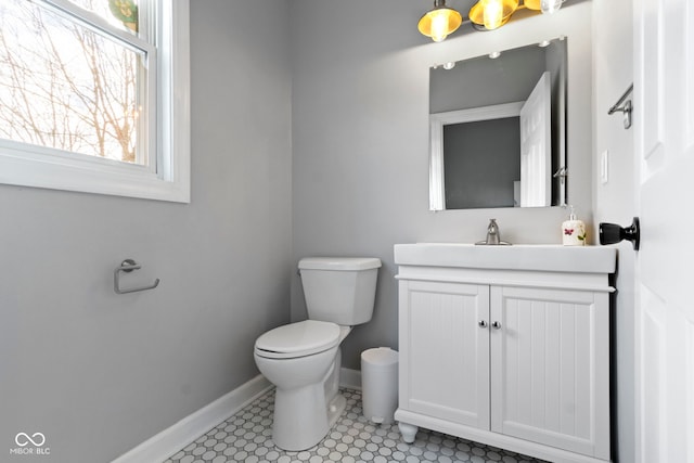 half bath featuring toilet, baseboards, and vanity