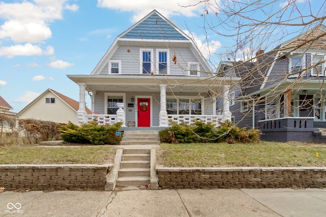 shingle-style home featuring a front lawn, covered porch, and a gambrel roof