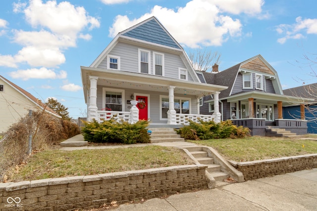 shingle-style home with a porch, a front yard, and a gambrel roof