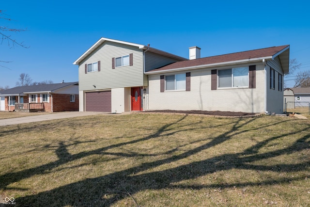 tri-level home featuring driveway, a front yard, a garage, brick siding, and a chimney