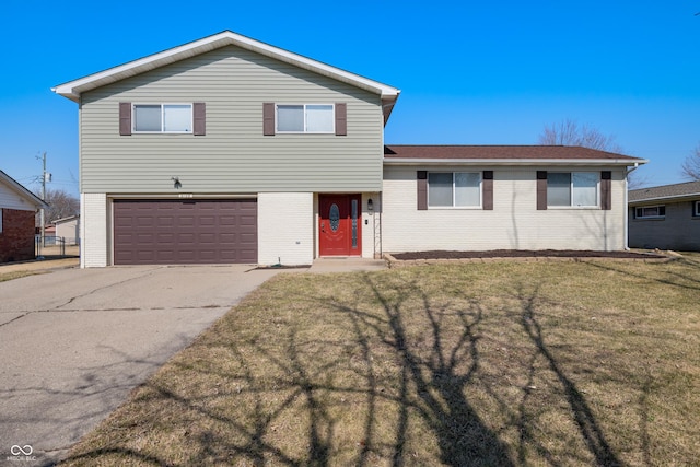 tri-level home featuring a front yard, brick siding, and an attached garage