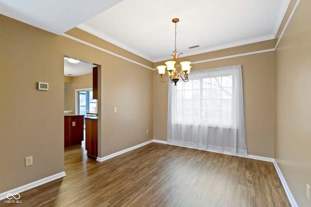 spare room featuring baseboards, visible vents, dark wood-style floors, ornamental molding, and a chandelier