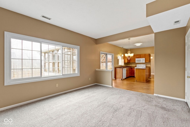 unfurnished living room with light carpet, baseboards, visible vents, and a notable chandelier