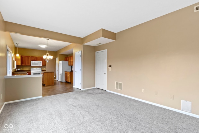 interior space featuring baseboards, dark colored carpet, visible vents, and an inviting chandelier