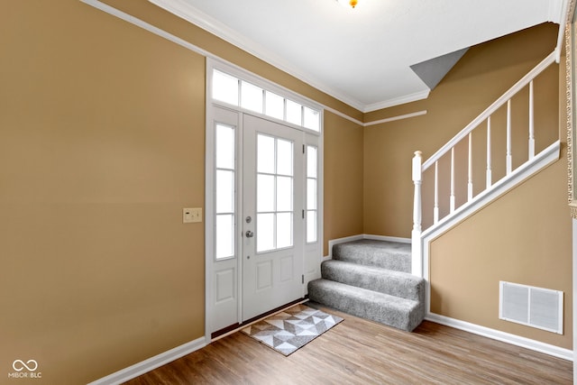 entryway with crown molding, visible vents, wood finished floors, baseboards, and stairs