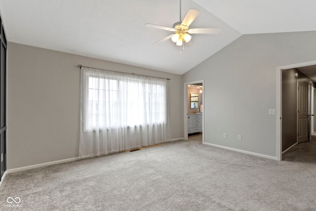 unfurnished bedroom with visible vents, baseboards, lofted ceiling, ensuite bath, and carpet flooring