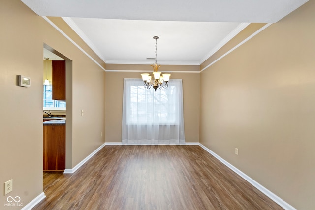 unfurnished dining area featuring a chandelier, crown molding, dark wood finished floors, and baseboards