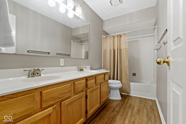 full bathroom with double vanity, toilet, a sink, and wood finished floors