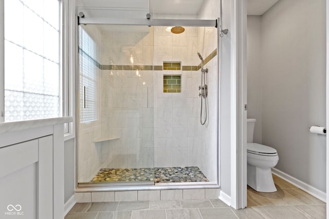 full bath with a stall shower, toilet, and baseboards