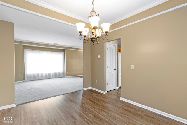 spare room with an inviting chandelier, crown molding, baseboards, and wood finished floors