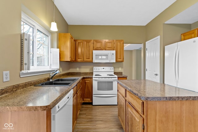 kitchen featuring white appliances, a sink, a center island, light wood finished floors, and dark countertops