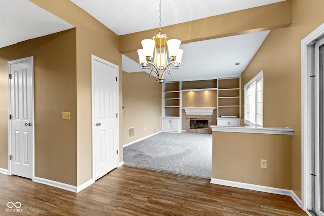 interior space featuring wood finished floors, a glass covered fireplace, visible vents, and baseboards