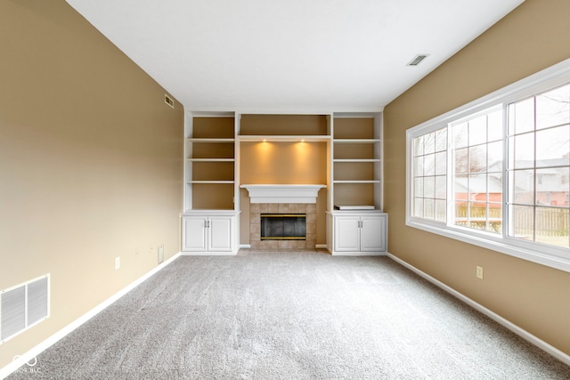 unfurnished living room featuring carpet floors, a tile fireplace, visible vents, and baseboards