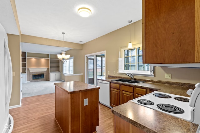 kitchen with dark countertops, white appliances, a kitchen island, and a sink