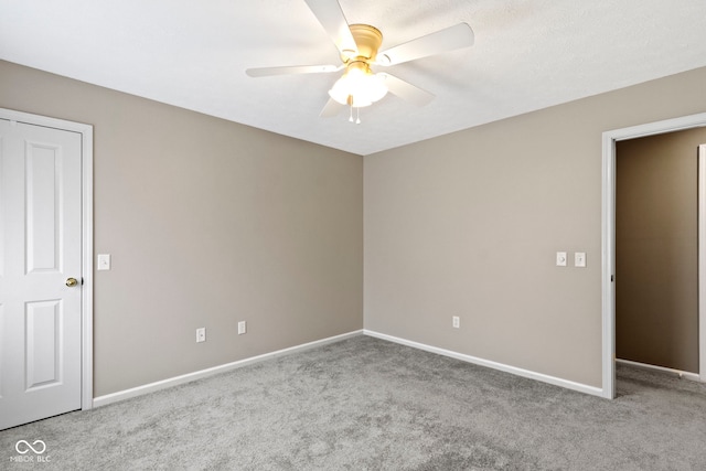 carpeted empty room with baseboards and a ceiling fan