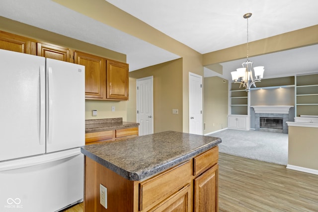 kitchen featuring dark countertops, a fireplace with flush hearth, freestanding refrigerator, and baseboards