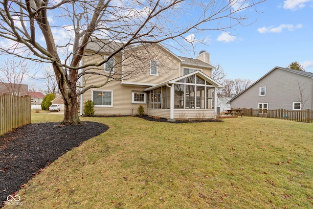 rear view of house featuring a sunroom, fence, a chimney, and a lawn