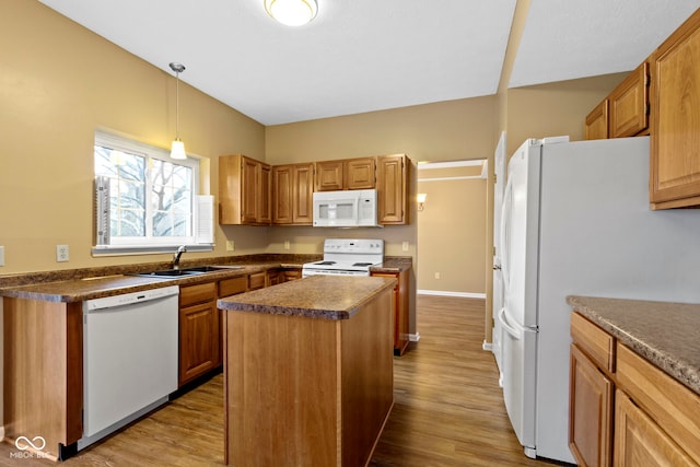 kitchen featuring dark countertops, white appliances, a sink, and a center island